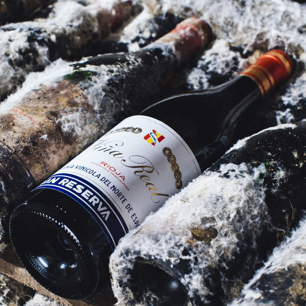 Clean Viña Real Gran Reserva Bottle in Wine Rack next to dusty old bottles