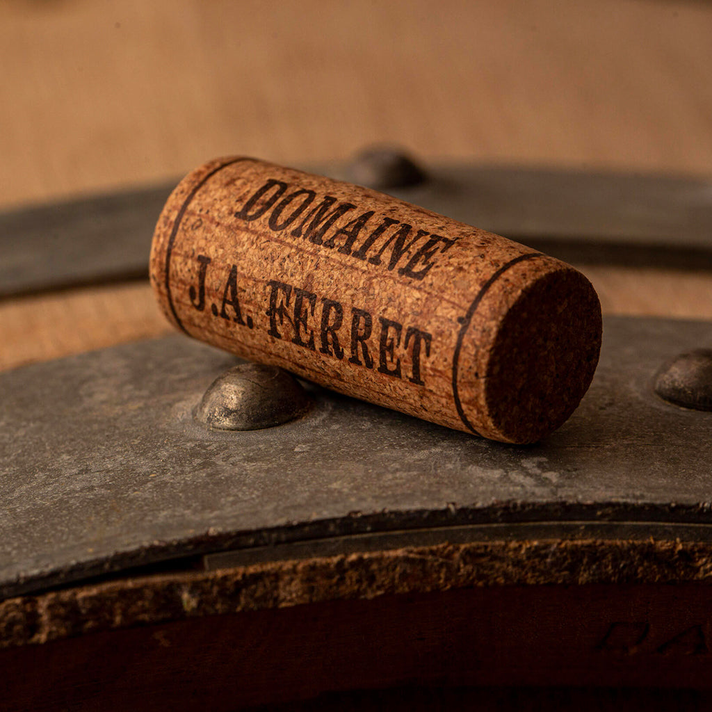 A Domaine J.A. Ferret Cork atop a wine barrel