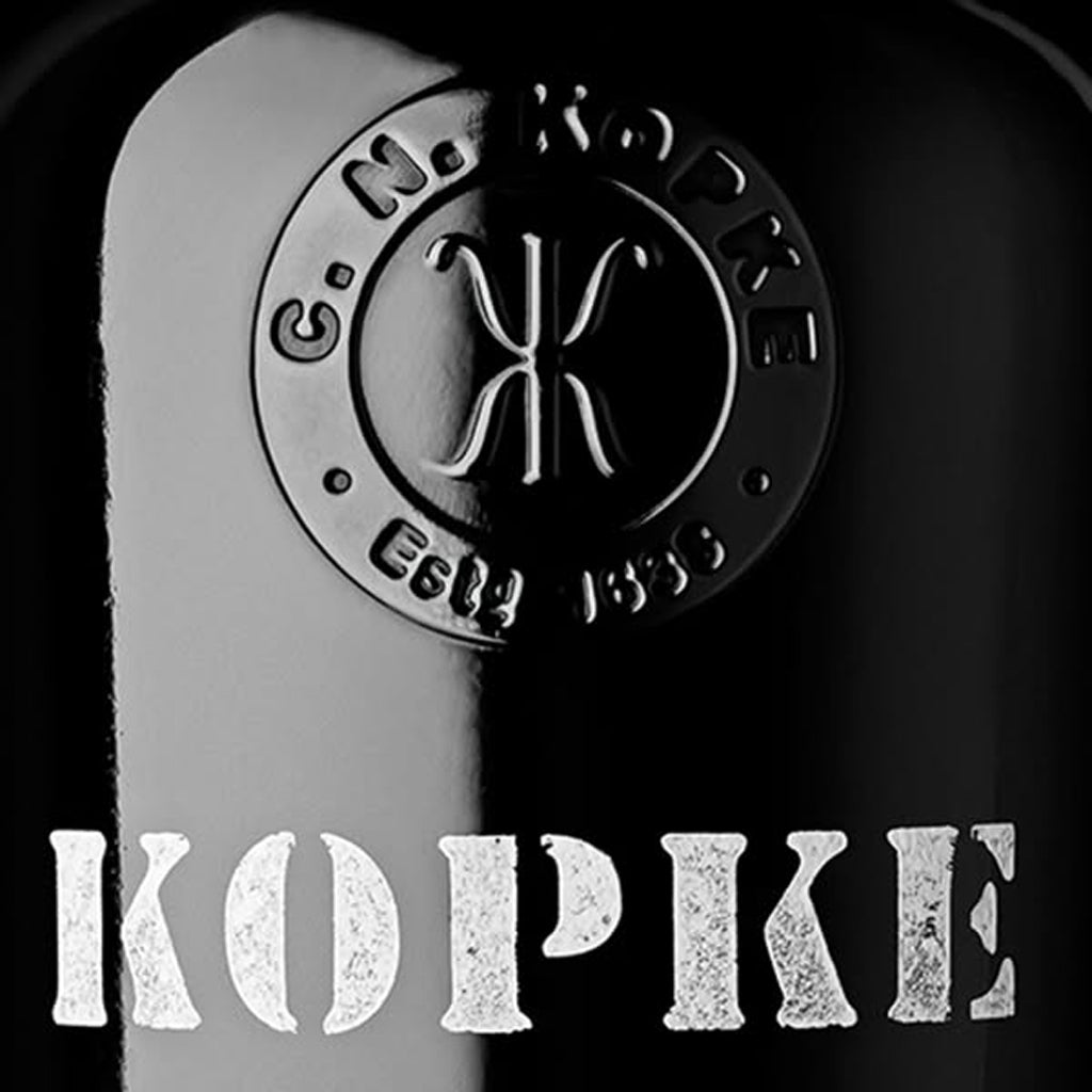 Close up bottle showing KOPKE stenciled in white on black bottle
